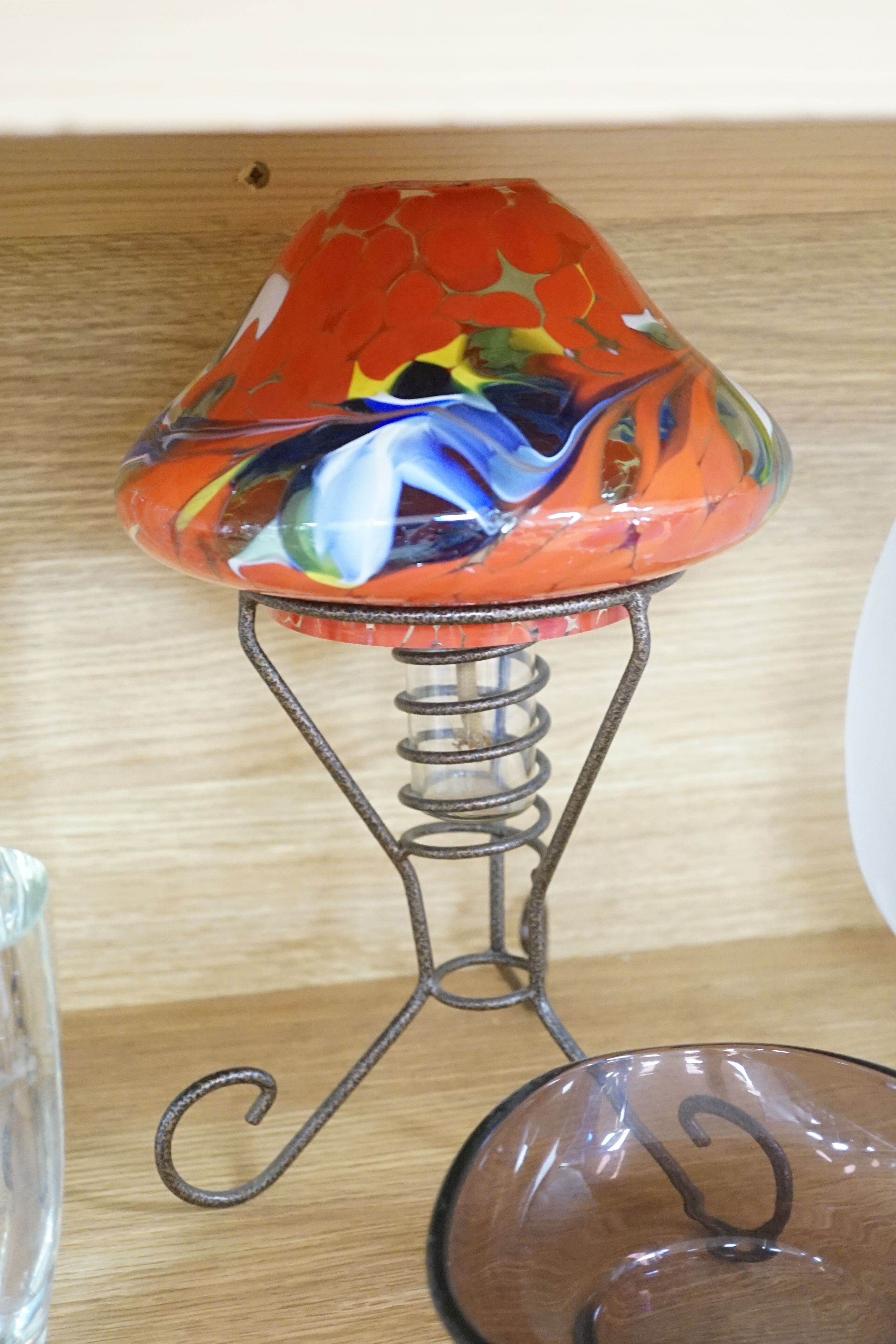 A frosted art glass bowl on stand with ‘face’ pattern to base together with an Iitalla map ash tray designed by Tapio Wirkkala, a bohemian iron and spatter pattern glass shade oil lamp, Tom Philabaum art glass perfume bo